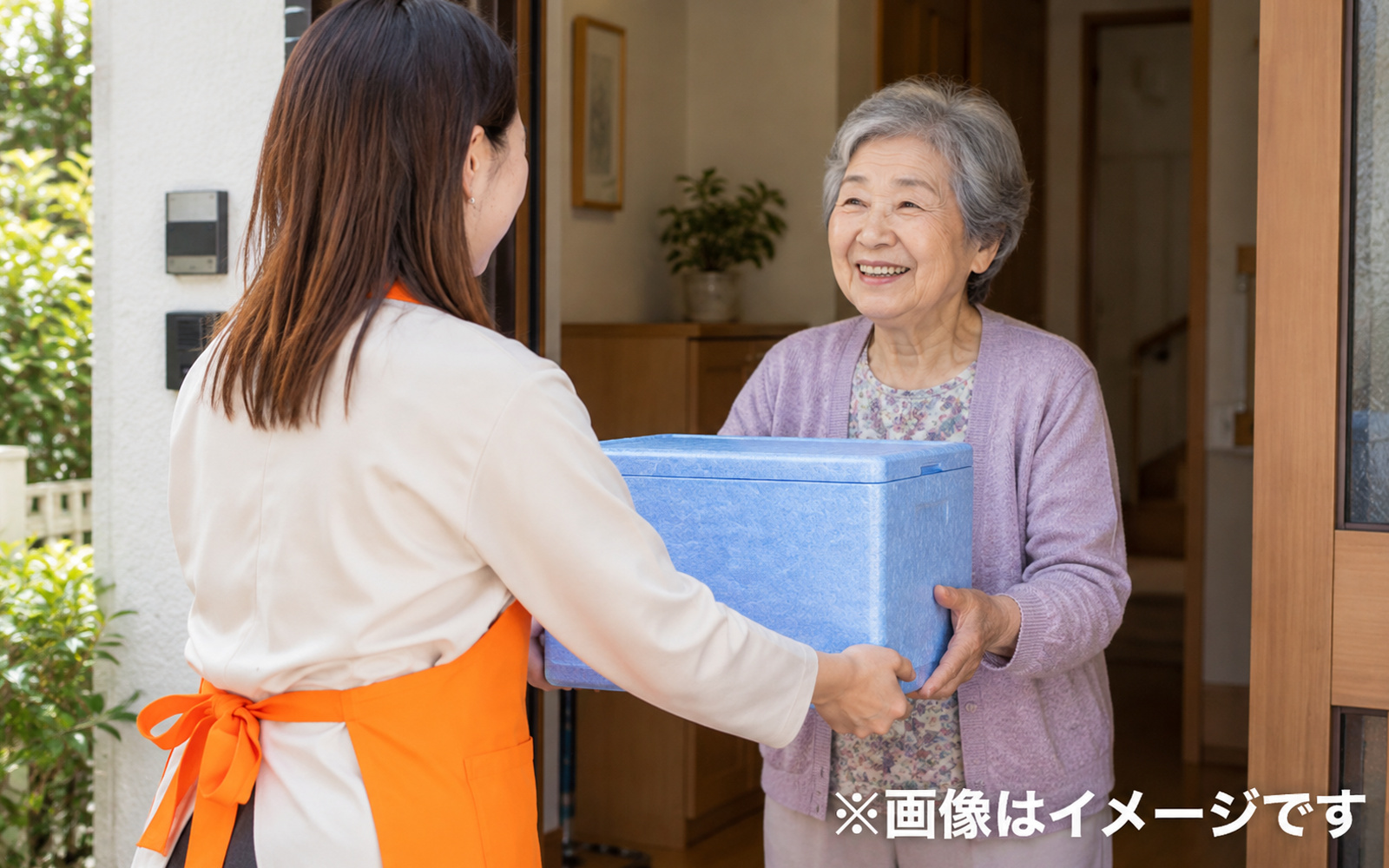 宅配食を玄関で受け取る場面のイメージ